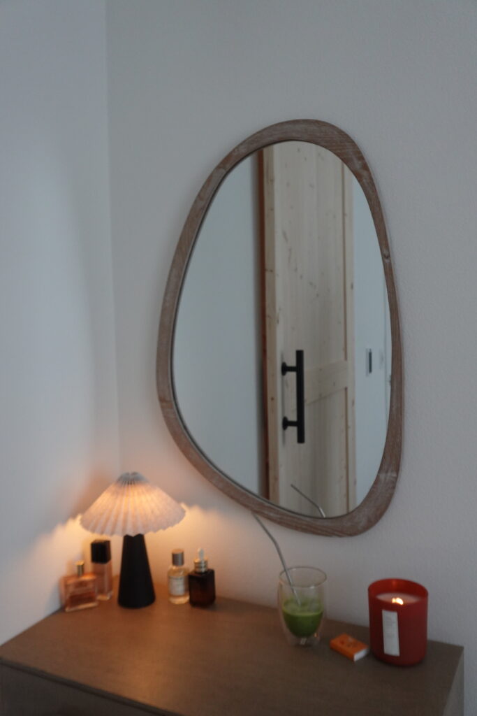 teardrop mirror and makeup vanity console table closeup wood tone