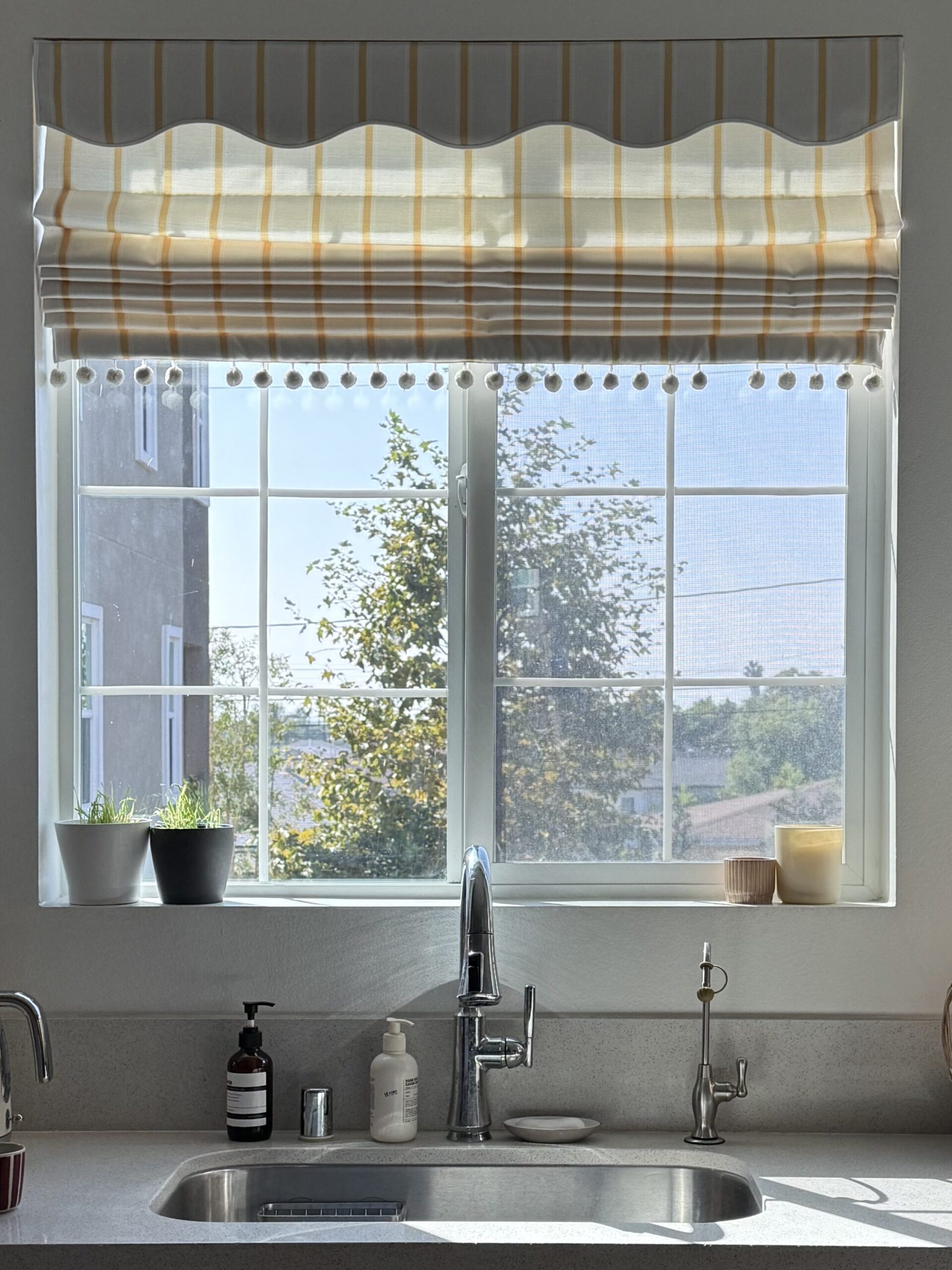 scalloped Roman shades in a yellow stripe on a west-facing kitchen window