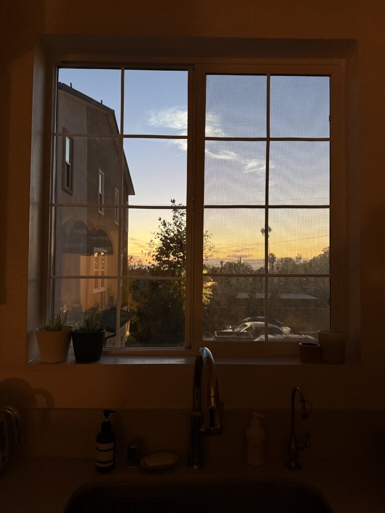white window grids framing a Los Angeles sunset from the kitchen sink